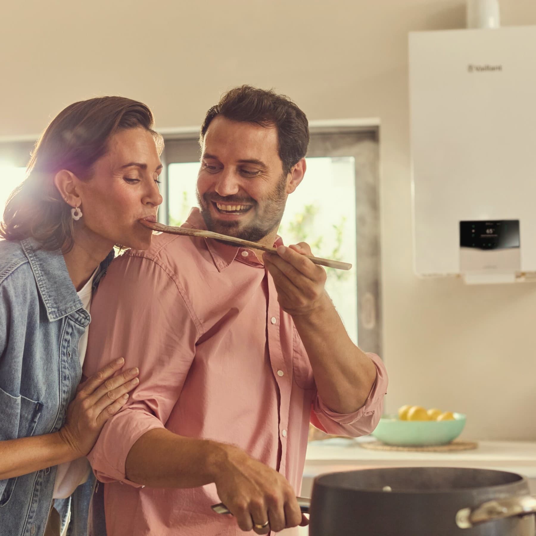 Man laat een vrouw proeven van een houten lepel, op de achtergrond zie je een Vaillant ecoTEC plus condensatiegasketel