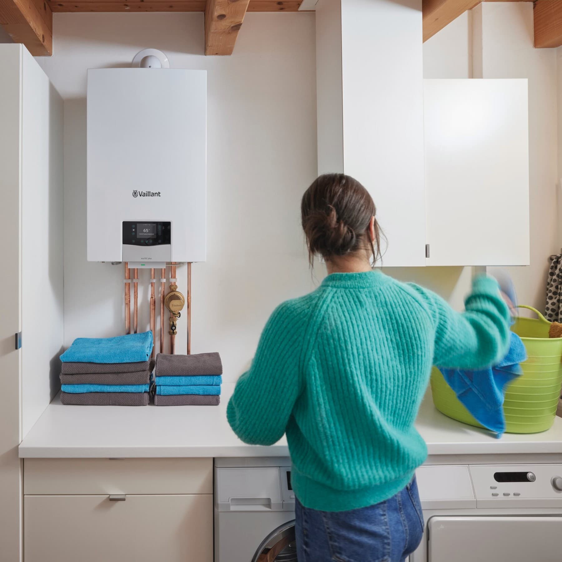 Vrouw doet de was met wandhangende ketel op de achtergrond