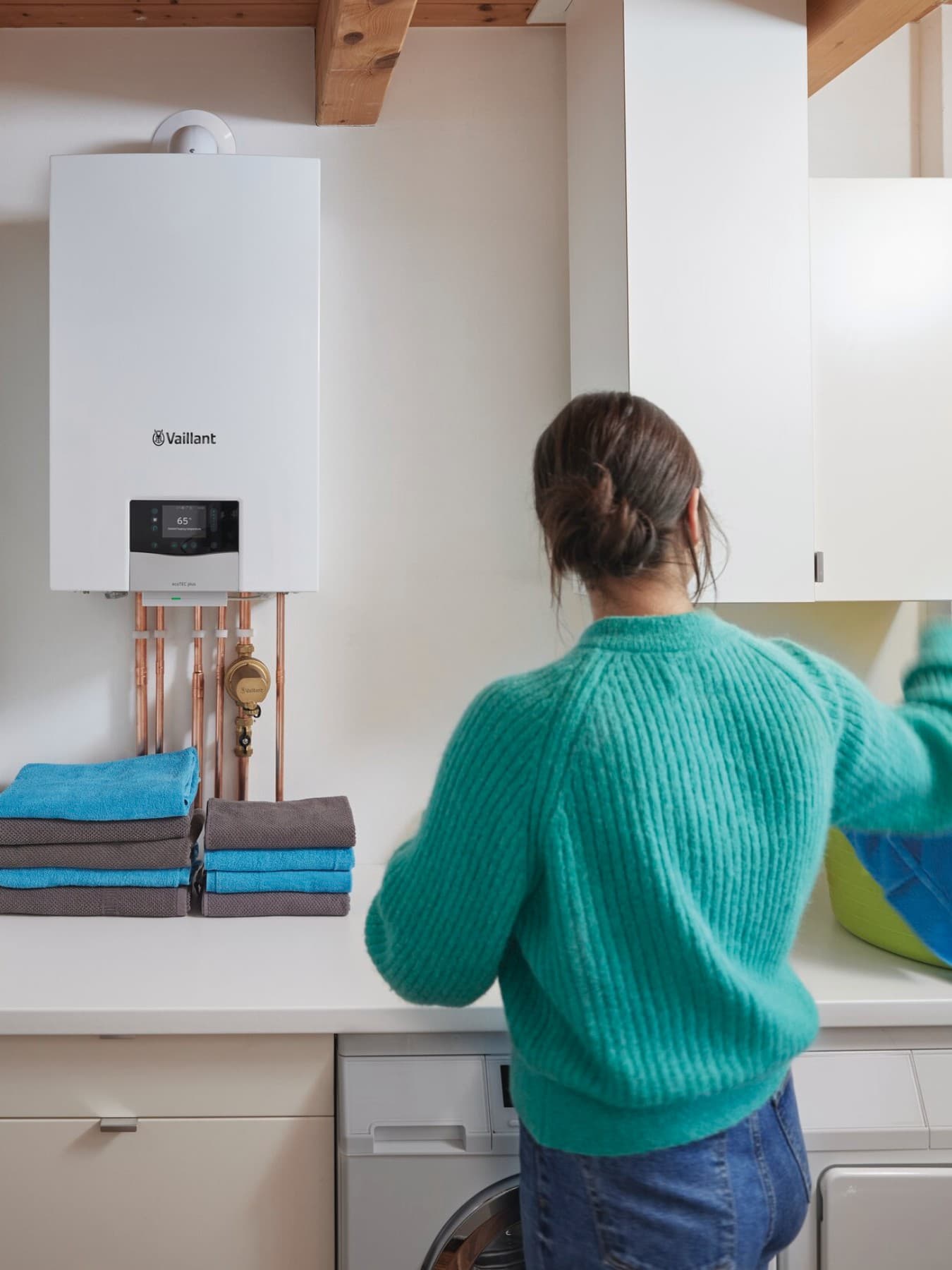 Vrouw doet de was met op de achtergrond een ketel en wandhangende boiler van Vaillant