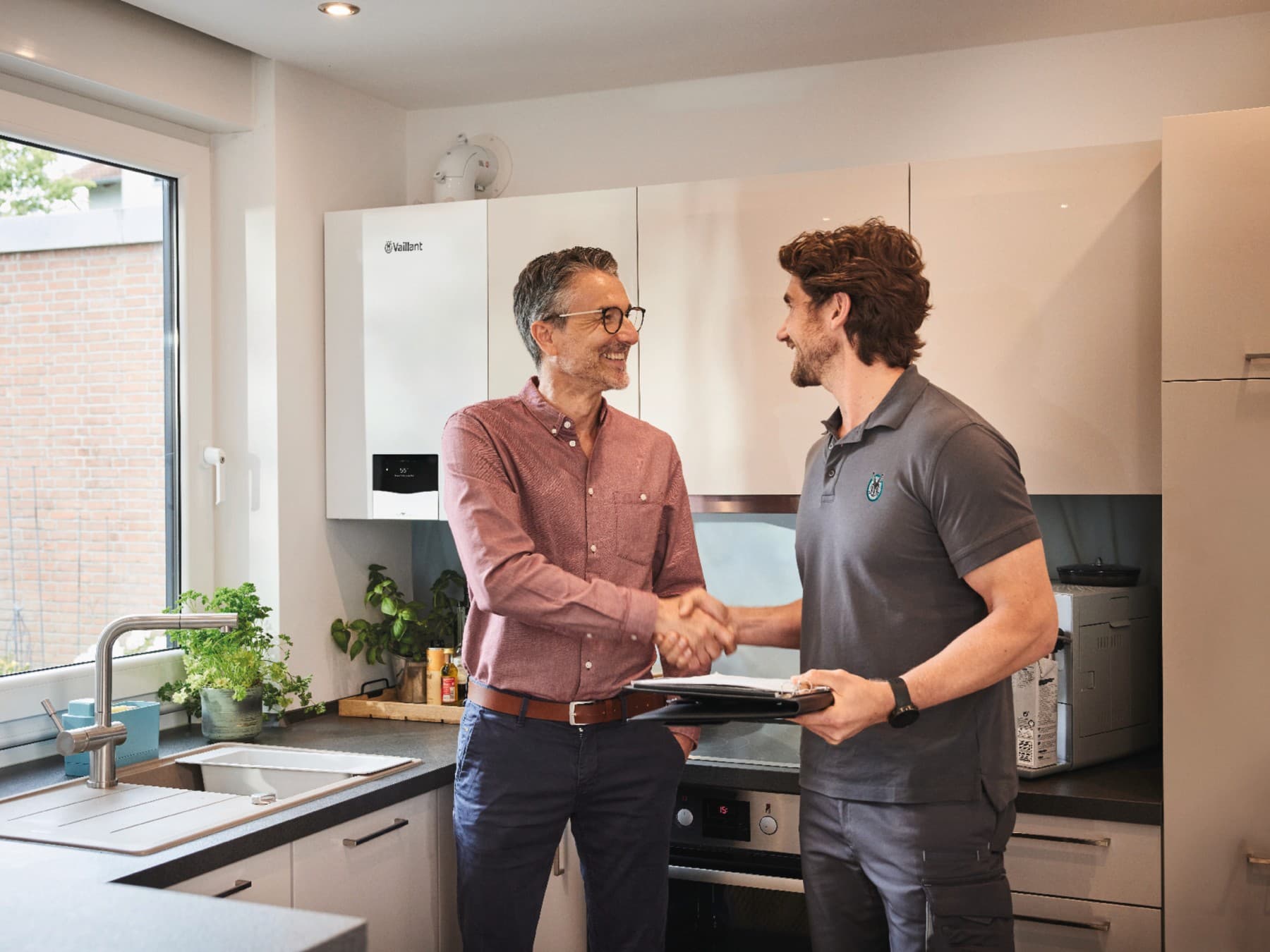 Klant en technieker schudden elkaar de hand in de keuken | Vaillant